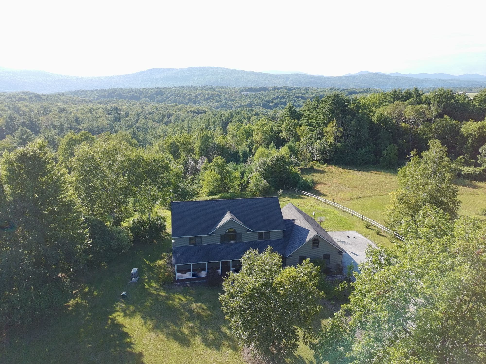 Aerial view of a home's deck, yard, and outbuildings