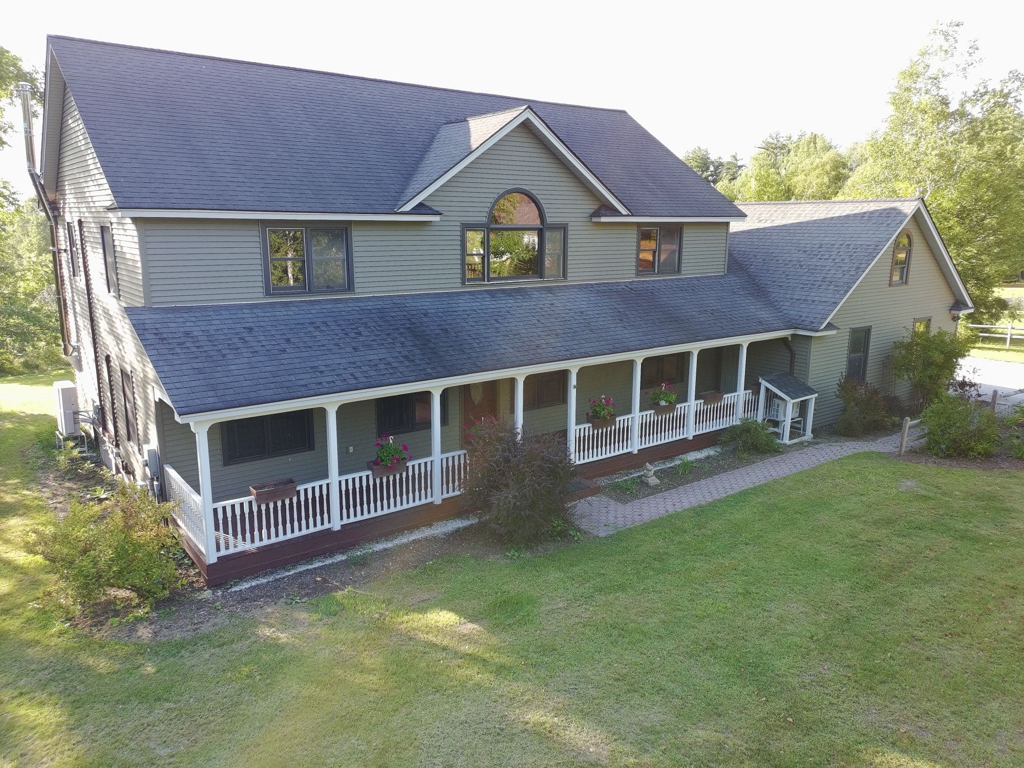 Aerial view of a home's driveway, garage, and front lawn